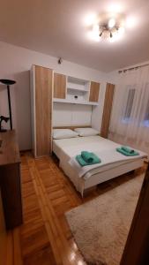 Schlafzimmer mit einem Bett mit weißer Bettwäsche und Holzböden in der Unterkunft Mihaela in Kaštela
