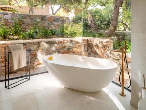 a white bath tub in a bathroom with a window at Cape Sounio, a Resort to Live in Sounio +55 photos