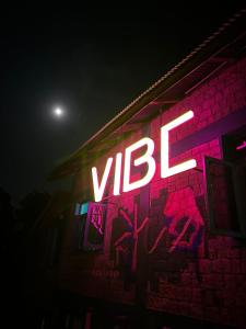 ein Neonschild auf der Seite eines Gebäudes mit Graffiti in der Unterkunft Vibe Hostel in Dharamshala