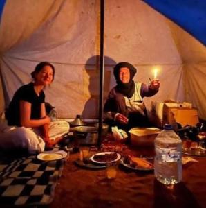 mężczyzna i kobieta siedzący w namiocie ze świecą w obiekcie Adventure dans le desert w mieście Tagounite