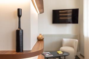 a living room with a black vase on a shelf at Brit Hotel Europ Bergerac in Bergerac