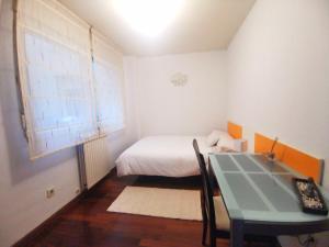 a small bedroom with a bed and a table at Habitación cerca del aeropuerto in Maliaño