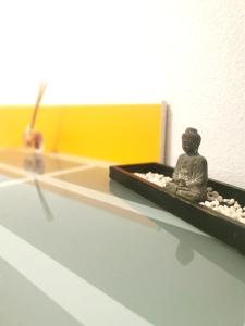 un pequeño buddha sentado en una bandeja en un estante en Habitación cerca del aeropuerto, en Maliaño