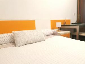 1 dormitorio con cama blanca y pared de color naranja en Habitación cerca del aeropuerto, en Maliaño