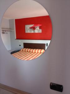 un miroir reflétant une chambre avec un lit et un mur rouge dans l'établissement Hotel motel residence Gonzaga, à Cantello