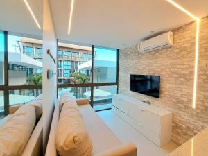 a living room with a couch and a tv at Flat no Centro de Porto de Galinhas -SUNNY HALL120 in Porto De Galinhas