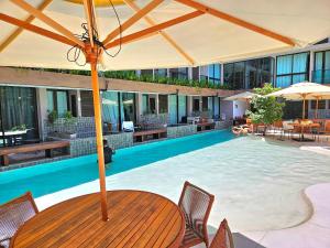 a swimming pool with a table and chairs and an umbrella at Flat no Centro de Porto de Galinhas -SUNNY HALL120 in Porto De Galinhas