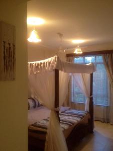 a bedroom with a canopy bed and a window at Bamburi Beach Homes in Bamburi