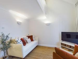 uma sala de estar com um sofá branco e uma televisão em “The Sleepers Cottage” 2-6 people w/ free parking em Hough Green