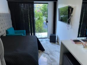 Habitación con mesa, TV y ventana. en Casa de Praia Barra Itanhangá, en Río de Janeiro