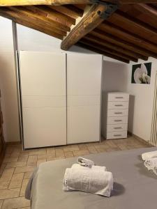 a bedroom with white cabinets and a bed with towels at Il Nido di Fede e Romy in Castelnuovo Berardenga