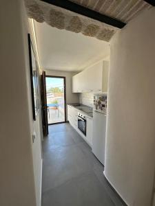 a kitchen with white appliances and a door to a patio at Scopello - Finestra sul cortile in Scopello