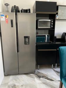 a stainless steel refrigerator in a kitchen with a microwave at Casa de Praia Barra Itanhangá in Rio de Janeiro