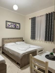 a bedroom with a bed and a table and curtains at VILA Eljus in Durrës