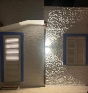 uma parede branca com duas janelas num quarto em Villa Bambi em Budoni