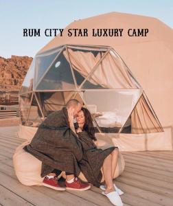 a man and woman laying on a bed in front of a tent at Rum city Star LUXURY Camp in Wadi Rum