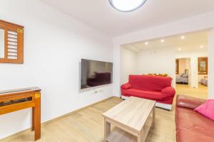 sala de estar con sofá rojo y TV en Casa Gómez, parking gratuito en Pleno Centro, en Almería