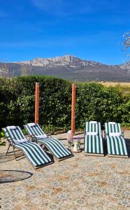 4 sillones alineados en un patio con montañas al fondo en Legado De Zabala, Casa Rural en Laguardia