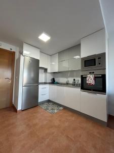 a kitchen with white cabinets and stainless steel appliances at La Isla in Isla de Arosa