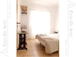 a bedroom with a bed and a table and a window at Casa Gil Anes in Almada