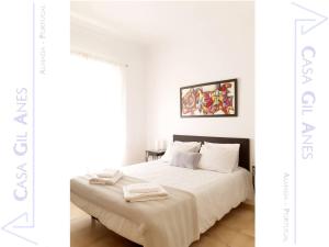 a white bedroom with a bed with white sheets at Casa Gil Anes in Almada