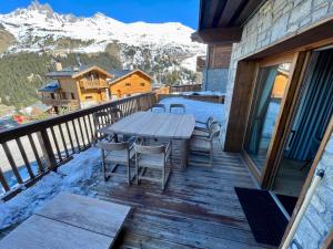 a wooden deck with a table and chairs on it at Appartement neuf à Mottaret / A12 in Les Allues
