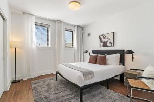 a white bedroom with a bed and two windows at Stylish 2BR Retreat in Hyde Park - Shoreland 1320 in Chicago