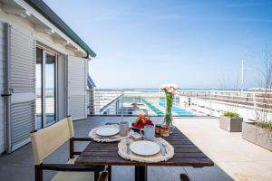 una mesa de madera con platos y flores en el balcón en Appartamento Luxury vista mare, en Lido di Camaiore