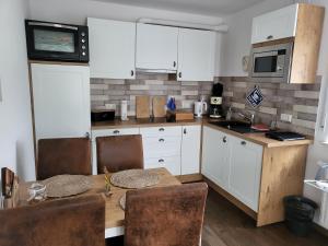 een keuken met witte kasten en een tafel en stoelen bij harle-casa.ostfriesland in Altfunnixsiel