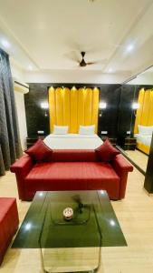 a living room with a red couch and a bed at Maple Tree, Lucknow - Couple Friendly in Lucknow
