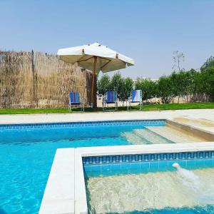 a swimming pool with an umbrella and two chairs at Dija's holiday rental in El-Qaṭṭa