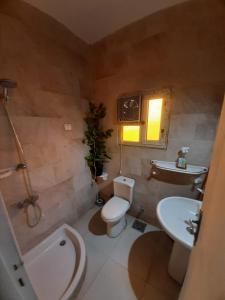 a bathroom with a toilet and a sink and a tub at Dija's holiday rental in Al Qaţā