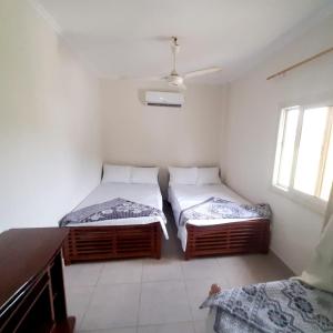 two beds in a room with white walls and windows at Dija's holiday rental in Al Qaţā
