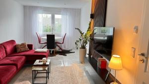 a living room with a red couch and a table at RelaxDays-Apartments in Gütersloh