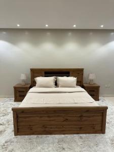 - une chambre avec un grand lit en bois et 2 tables de chevet dans l'établissement وحدة سكنية فاخرة 2 Luxury residential unit, à Médine