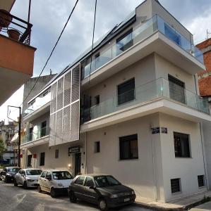 a white building with cars parked in front of it at MELIGEO APARTMENTS CENTER of IOANNINA in Ioannina