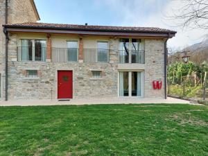uma casa de tijolos com uma porta vermelha e um quintal em BORGO LE LANTERNE Locazione Turistica em Follina