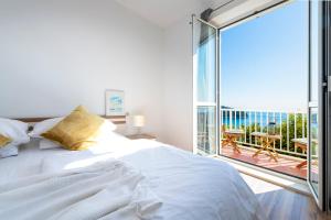 a bedroom with a large white bed and a balcony at Chill Out - Old Town & Seaview Apartments in Dubrovnik