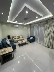 una sala de estar con 2 sofás azules y una mesa. en شاليهات حديقة الوسام en Taif