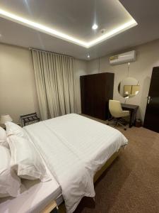 a bedroom with a large white bed and a desk at شاليهات حديقة الوسام in Taif