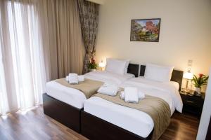 Hotel Padelidaki في تريكالا: غرفة نوم بسريرين عليها مناشف بيضاء