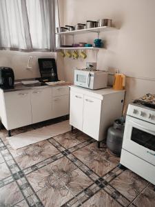 eine Küche mit weißen Schränken und einer Mikrowelle in der Unterkunft Kitnet OKTOBERFEST in Blumenau