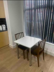 Roundhay的住宿－*Cosy 1 bedroom apt nxt to Roundhay and centre *，一张白色的桌子和两把椅子以及窗户