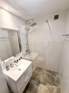 a white bathroom with a sink and a shower at Apartament Ustecka Syrenka in Ustka