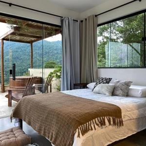 a bedroom with a large bed and a large window at Segunda Casa in Paraty
