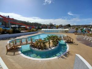 une piscine avec palmiers et montagnes russes dans l'établissement Mobil home équipé camping 5*, à Houlgate