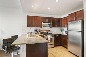 a kitchen with wooden cabinets and a stainless steel refrigerator at Chic & Elite 1BR Apartment in Hyde Park - Shoreland 714 in Chicago