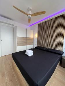 a bedroom with a black bed with a ceiling fan at Hany apartment Tropic mar 18-C in Benidorm