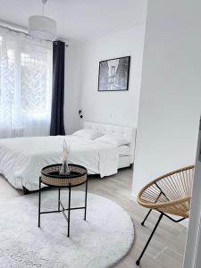 a white bedroom with a bed and a table and a chair at Appartement hyper centre - Coty in Le Havre