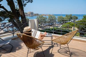 a woman sitting in a chair reading a book on a balcony at Key Largo in Bandol